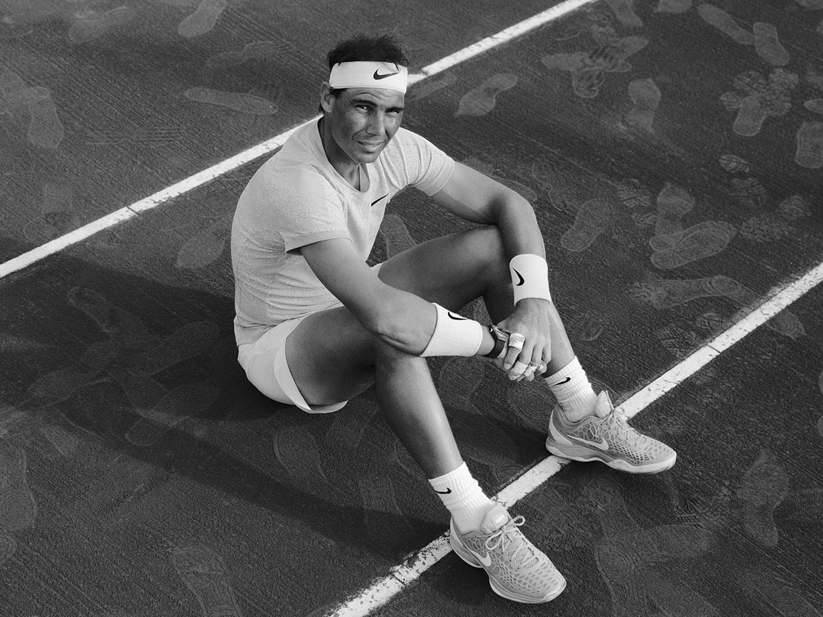 El tenista Rafa Nadal sentado en el suelo de una pista de tenis con un reloj Richard Mille en la muñeca.