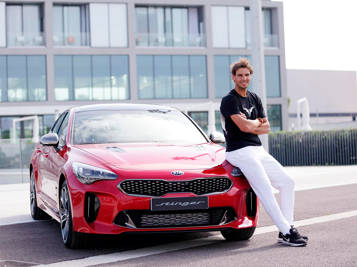 Rafa Nadal de joven posando junto a su Kia Stinger GT rojo.