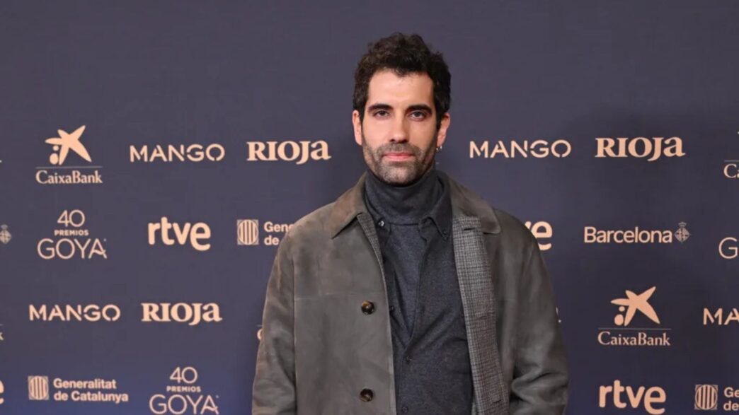 El actor Tamas Novas con chaqueta gris y jersey gris posando en el photocall de la cena de nominados de los 40 Premios Goya.