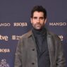 El actor Tamas Novas con chaqueta gris y jersey gris posando en el photocall de la cena de nominados de los 40 Premios Goya.