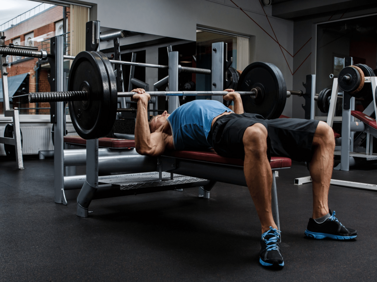 Hombre realizando press de banca con barra en entrenamiento de fuerza para ganar masa muscular