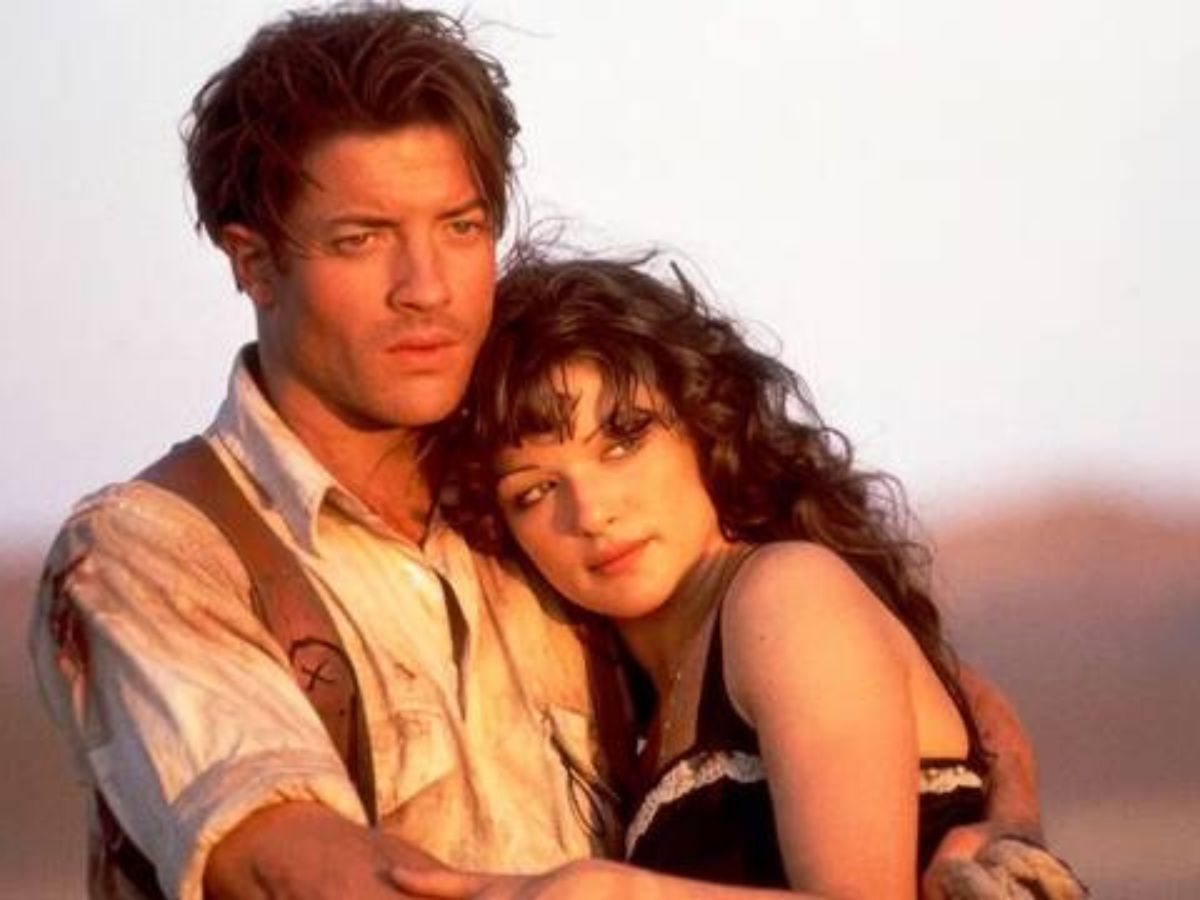 Brendan Fraser con camisa blanca abrazando a Rachel Weisz al atardecer en una escena de la película La Momia.