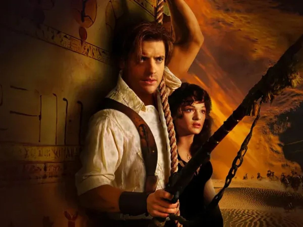 Brendan Fraser con camisa blanca y sujetando un arma con Rachel Weisz a su lado en Egipto en una escena de La Momia.