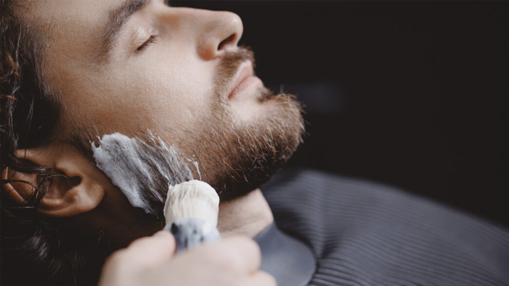 hombre afeitándose en una barbería con espuma en la barba