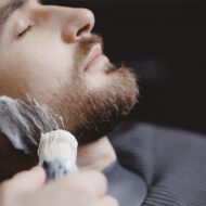 Las mejores afeitadoras eléctricas y recortadoras de barba para hombre de 2026 a prueba hombre afeitándose en una barbería con espuma en la barba