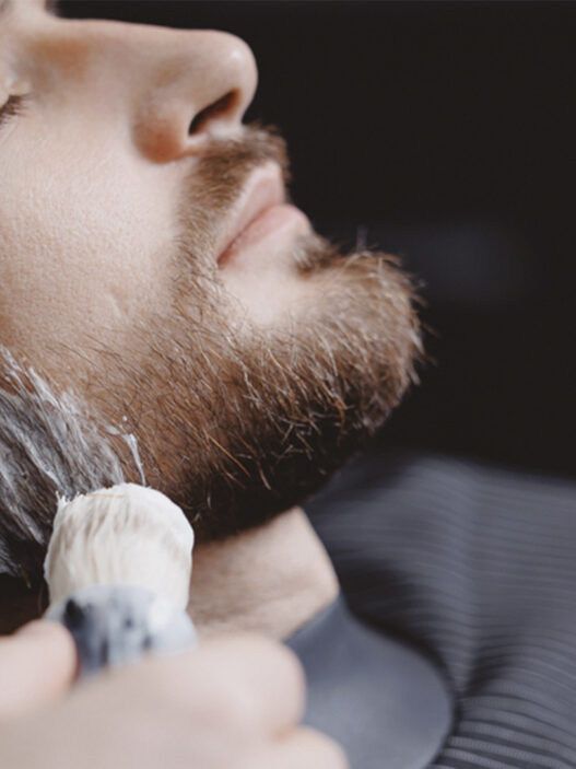 hombre afeitándose en una barbería con espuma en la barba