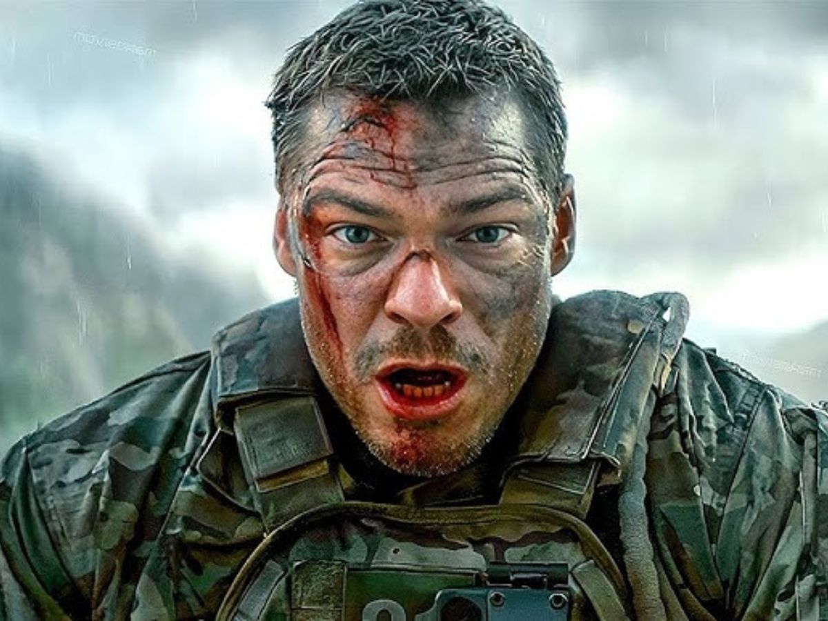 Primer plano de Alan Ritchson con sangre en la cara y en la boca y vestido de militar para la película Máquina de Hierro.