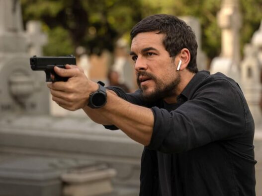 Mario Casas con un jersey negro apuntando con una pistola en una escena de la película Zeta.