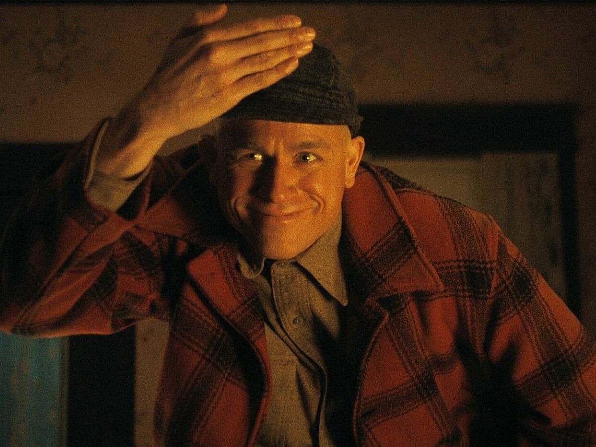 Charlie Hunnam con un gorro y una chaqueta de cuadros rojos interpretando a Ed Gein en la ficción de Netflix.