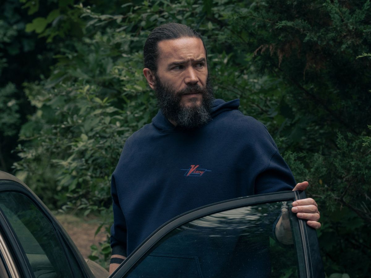 Tom Pelphrey con barba y sudadera azul en el bosque en una escena de la exitosa serie Task.