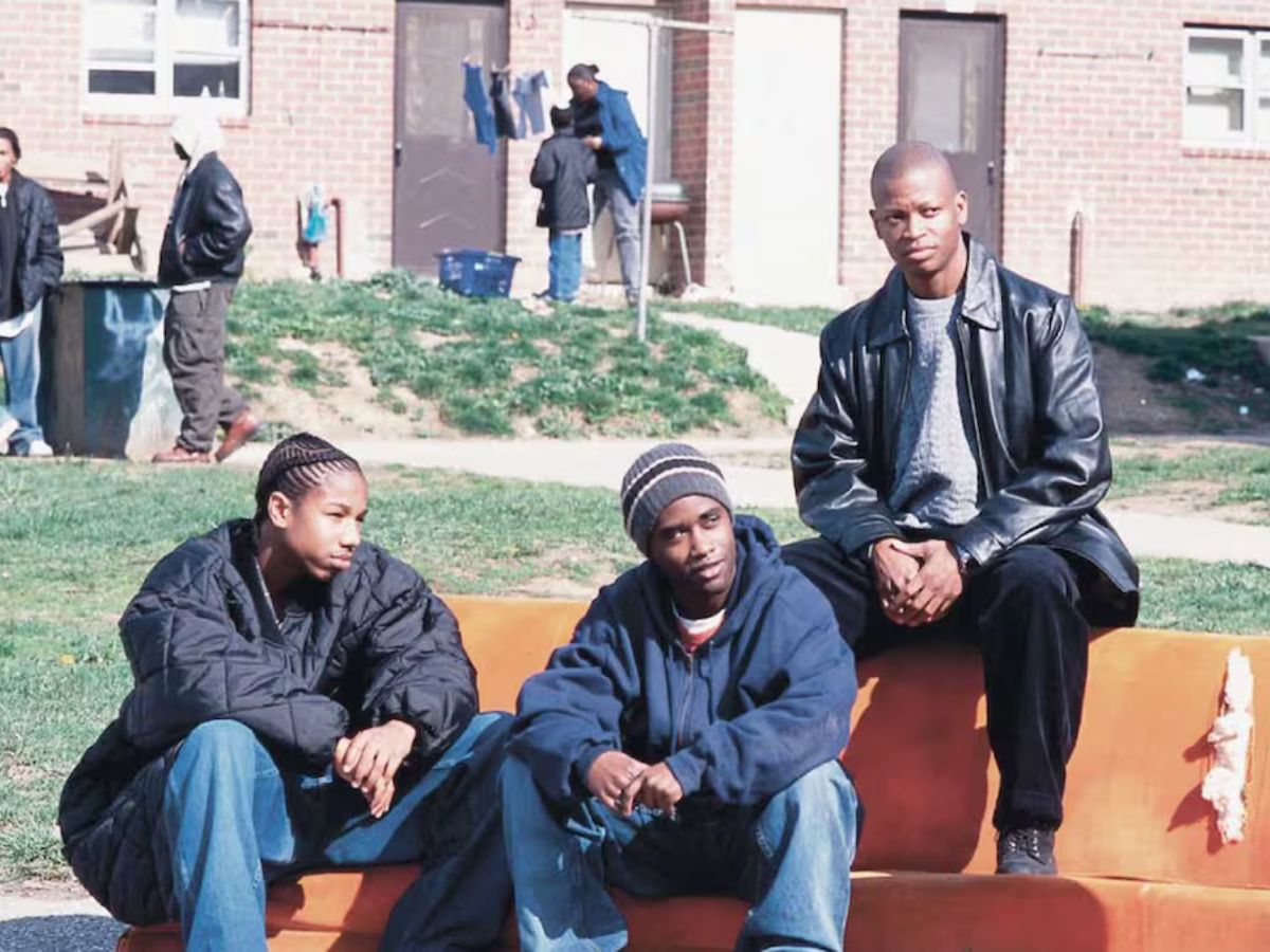 Escena de The Wire con tres de los protagonistas sentados en un banco al sol.