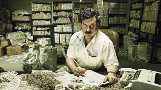 Andrés Parra rodeados de papeles y billetes interpretando a Pablo Escobar en la serie Pablo Escobar: el patrón del mal.