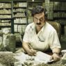 Andrés Parra rodeados de papeles y billetes interpretando a Pablo Escobar en la serie Pablo Escobar: el patrón del mal.