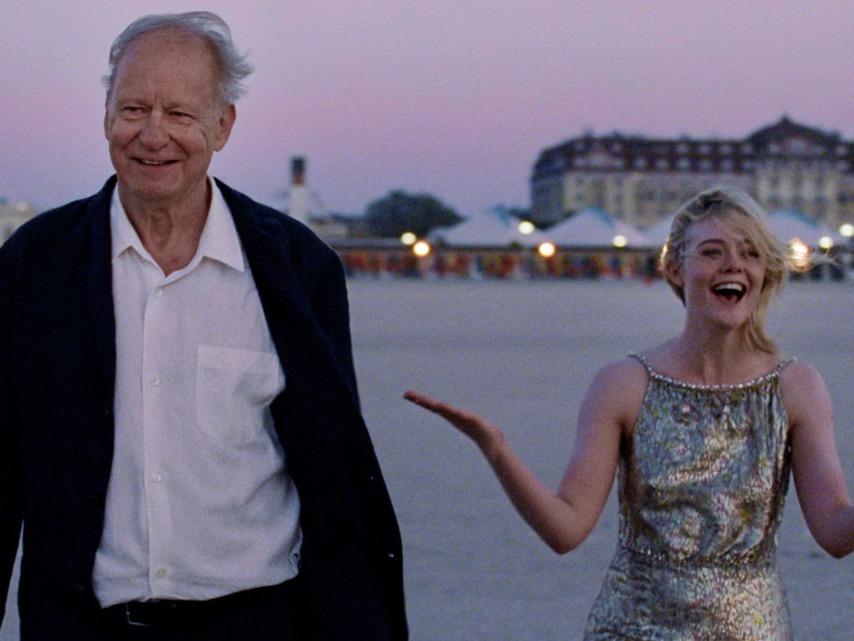 Stellan Skarsgård con chaqueta negra y camisa blanca y detrás Elle Faning con un lago de fondo como parte de la película Valor Sentimental.