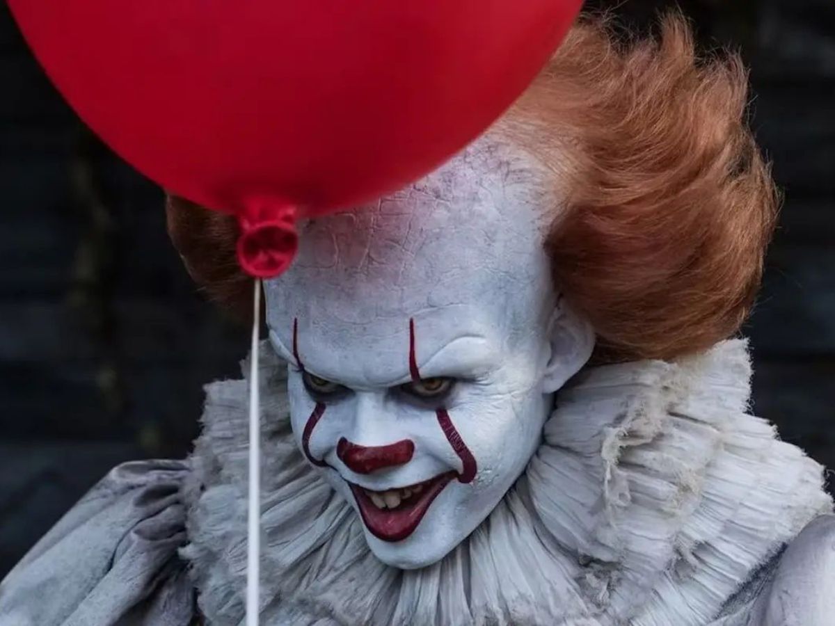 Primer plano de Pennywise con un globo rojo, el payaso protagonista de la serie It: bienvenidos a Derry.