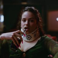 Primer vistazo a Rosalía en la tercera temporada de Euphoria y todo lo que sabemos de su personaje Rosalía con un collarín y bebiendo un refresco con pajita interpretando a Magick, una bailarina de pole dance en Euphoria.