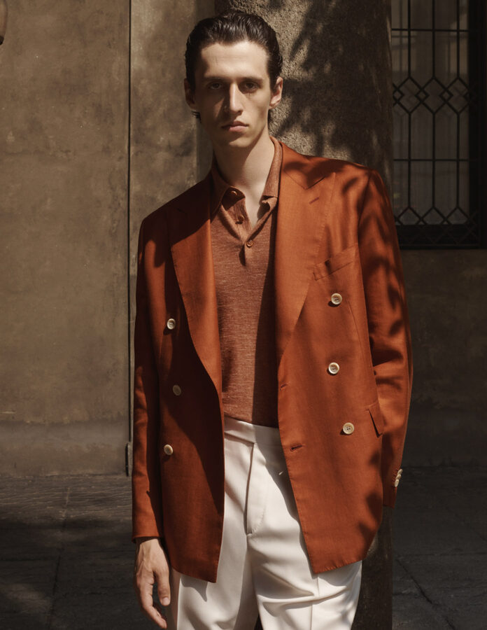 Outfit elegante de Brioni que combina blazer color marron con pantalón blanco y polo de punto camel