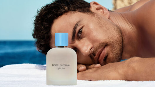 modelo tumbado en toalla mirando perfume Dolce & Gabbana