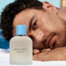 modelo tumbado en toalla mirando perfume Dolce & Gabbana
