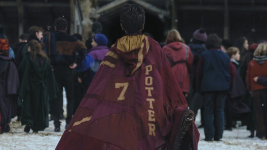 Primeras imágenes serie Harry Potter y la piedra filosofal, en la que se ve a Hary Potter con la capa de espaldas a la cámara.