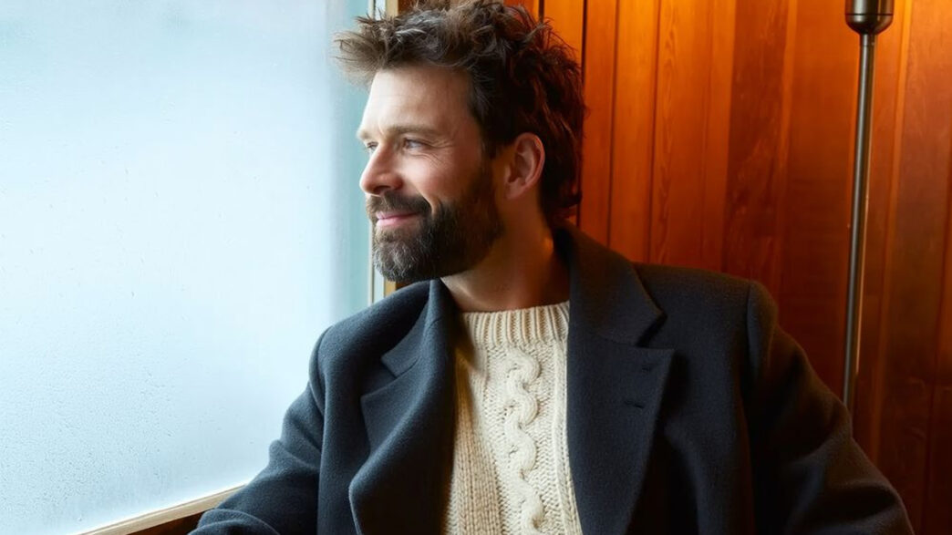 Hombre elegante con barba cuidada mirando por una ventana