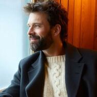 Cuidado de la barba: los 5 productos imprescindibles que recomiendan los expertos Hombre elegante con barba cuidada mirando por una ventana