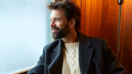 Hombre elegante con barba cuidada mirando por una ventana