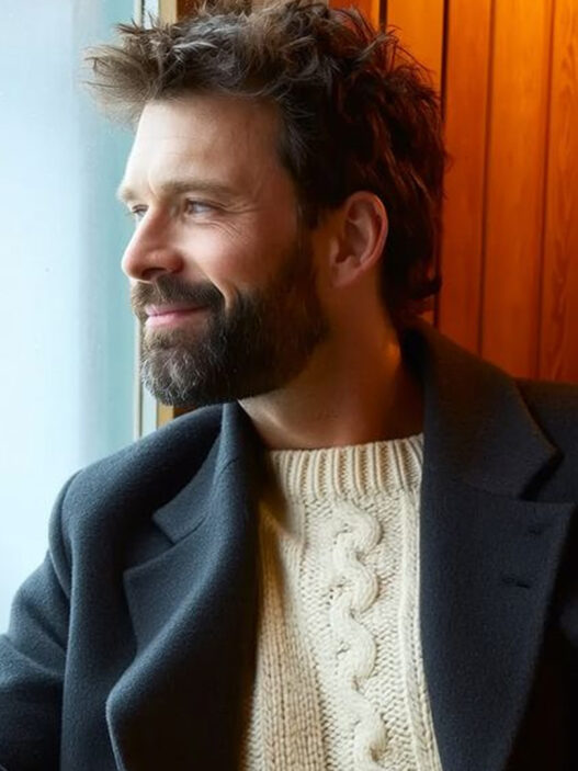 Hombre elegante con barba cuidada mirando por una ventana