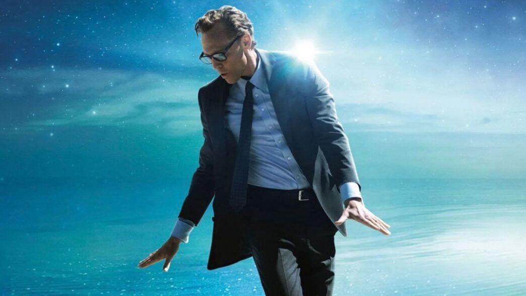 Tom Hiddleston con traje y corbata sobre un fondo azul protagoniza La vida de Chuck, adaptación de Stephen King en Prime Vídeo.