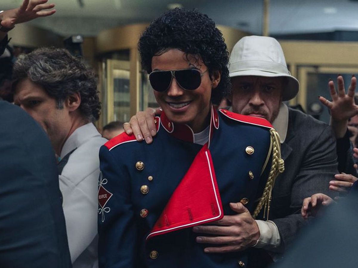 Jaafar Jackson como Michael Jackson con chaqueta militar azul y roja, gafas de aviador y rodeado de fans y seguridad
