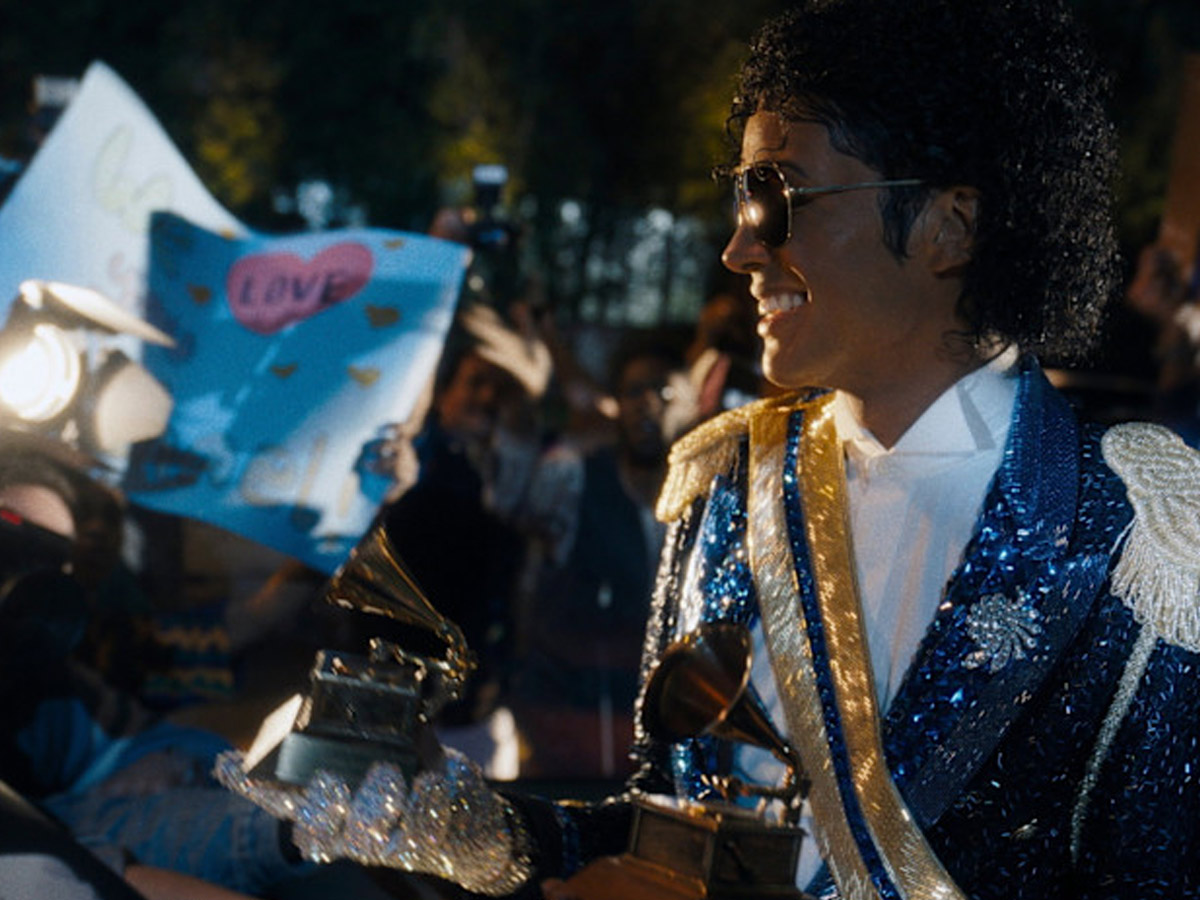 Jaafar Jackson como Michael Jackson sosteniendo varios premios Grammy rodeado de fans en el biopic