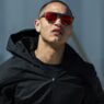 Hombre con chaqueta negra con capucha y gafas Mó Sport Fiber de lentes espejadas rojas mirando al horizonte