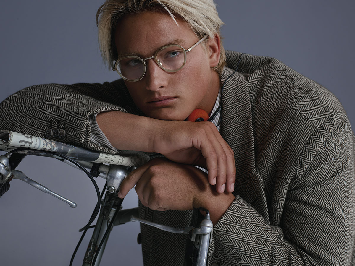 Modelo con chaqueta de espiga de Armani/Archivio apoyado en una bicicleta vintage