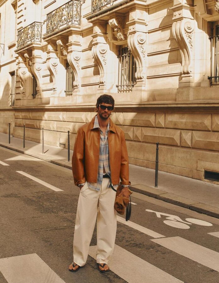 Estilo masculino con pantalones balloon de Zara blancos combinados con chaqueta de cuero y bolso de mano.