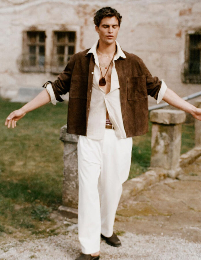 Pantalón blanco chino wide fit de Zara con camisa blanca, sobrecamisa de ante marrón y mules en estilismo boho primavera 2026