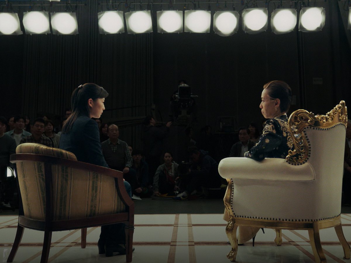 Kazuko Hosoki sentada en un trono dorado durante una entrevista televisiva en la serie de Netflix