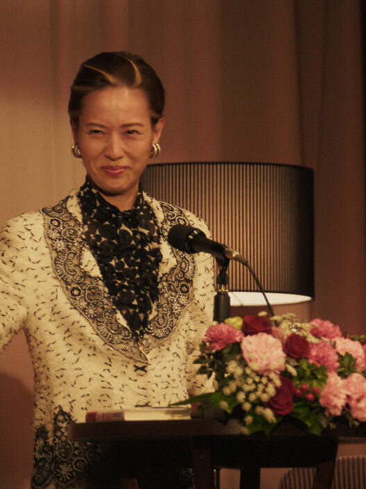 Erika Toda interpreta a Kazuko Hosoki dando una conferencia en la miniserie de Netflix Te irás al infierno