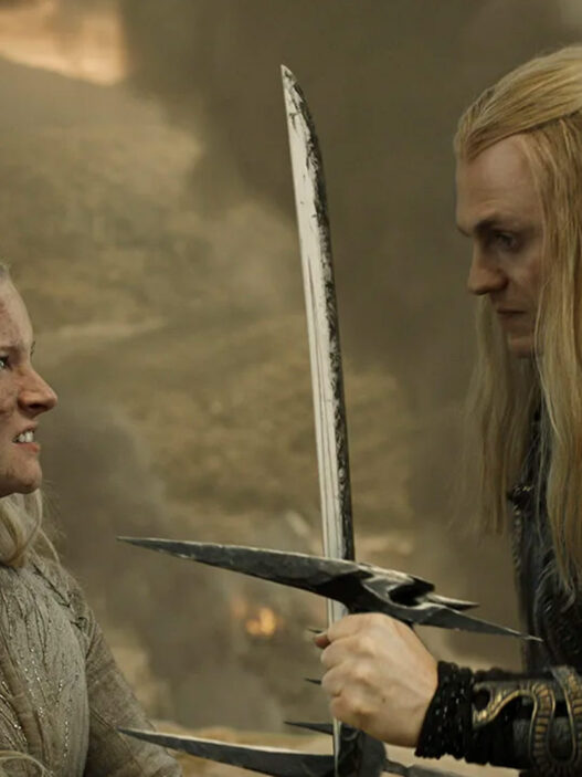 Sauron amenaza con una espada a Galadriel apoyada contra un muro de piedra en una escena de 'Los anillos del poder'.