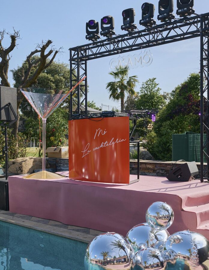Escenario de DJ junto a la piscina en Casa Mó con una copa de cóctel gigante y bolas plateadas