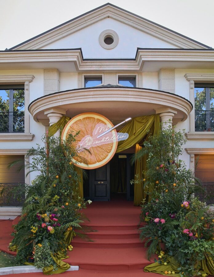 Entrada decorada de Casa Mó con una rodaja de naranja gigante, flores y alfombra roja