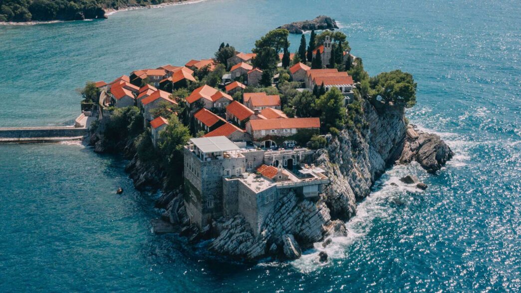 Vista aérea del pueblo amurallado de Sveti Stefan con casas de piedra y tejados de teja roja sobre el Adriático