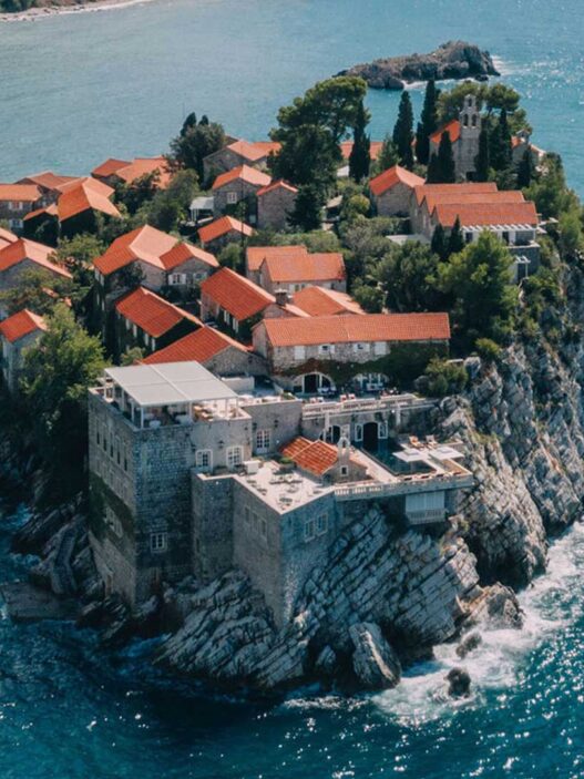 Vista aérea del pueblo amurallado de Sveti Stefan con casas de piedra y tejados de teja roja sobre el Adriático