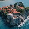 Vista aérea del pueblo amurallado de Sveti Stefan con casas de piedra y tejados de teja roja sobre el Adriático