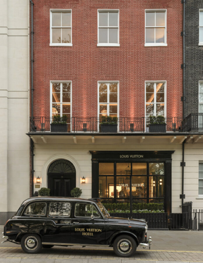Fachada del Louis Vuitton Hotel London en Berkeley Square, Mayfair, con un taxi negro clásico personalizado aparcado en la entrada