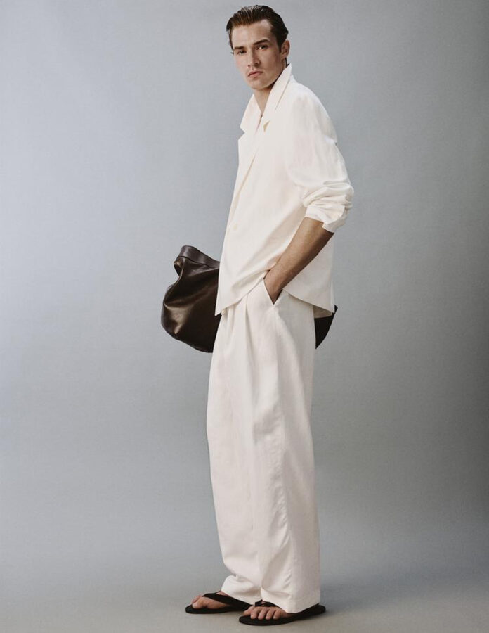 Vista de perfil del traje blanco de lino relaxed fit de Zara para hombre combinado con sandalias de piel marrón