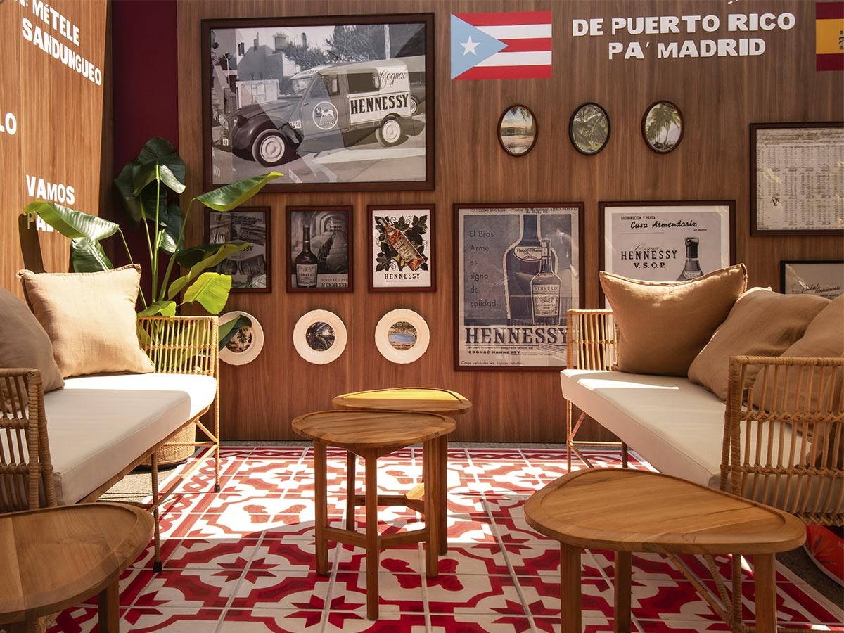 Interior del stand Hennessy Clúb decorado con carteles antiguos de Hennessy, banderas de Puerto Rico y España y suelo hidráulico rojo