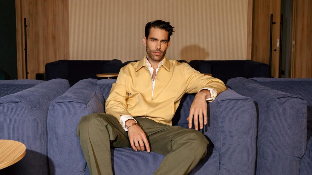 Jon Kortajarena sentado en el sofá de una zona común de Be Casa con chaqueta amarilla