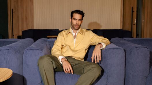 Jon Kortajarena sentado en el sofá de una zona común de Be Casa con chaqueta amarilla