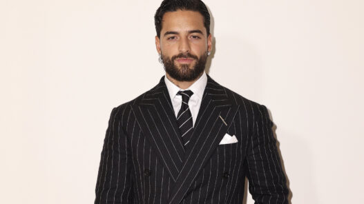 Retrato de Maluma con traje de raya diplomática y corbata negra en el desfile de Ralph Lauren