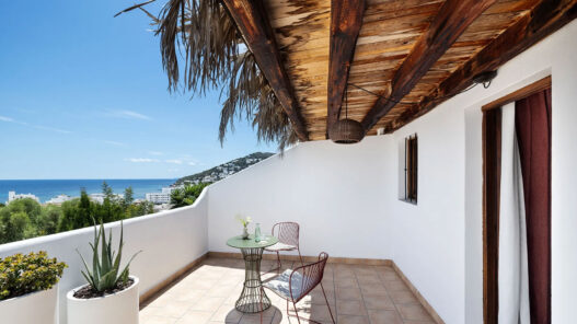 Terraza de One Shot Buenavista en Ibiza con techo de madera, paja y vistas al mar de Santa Eulalia